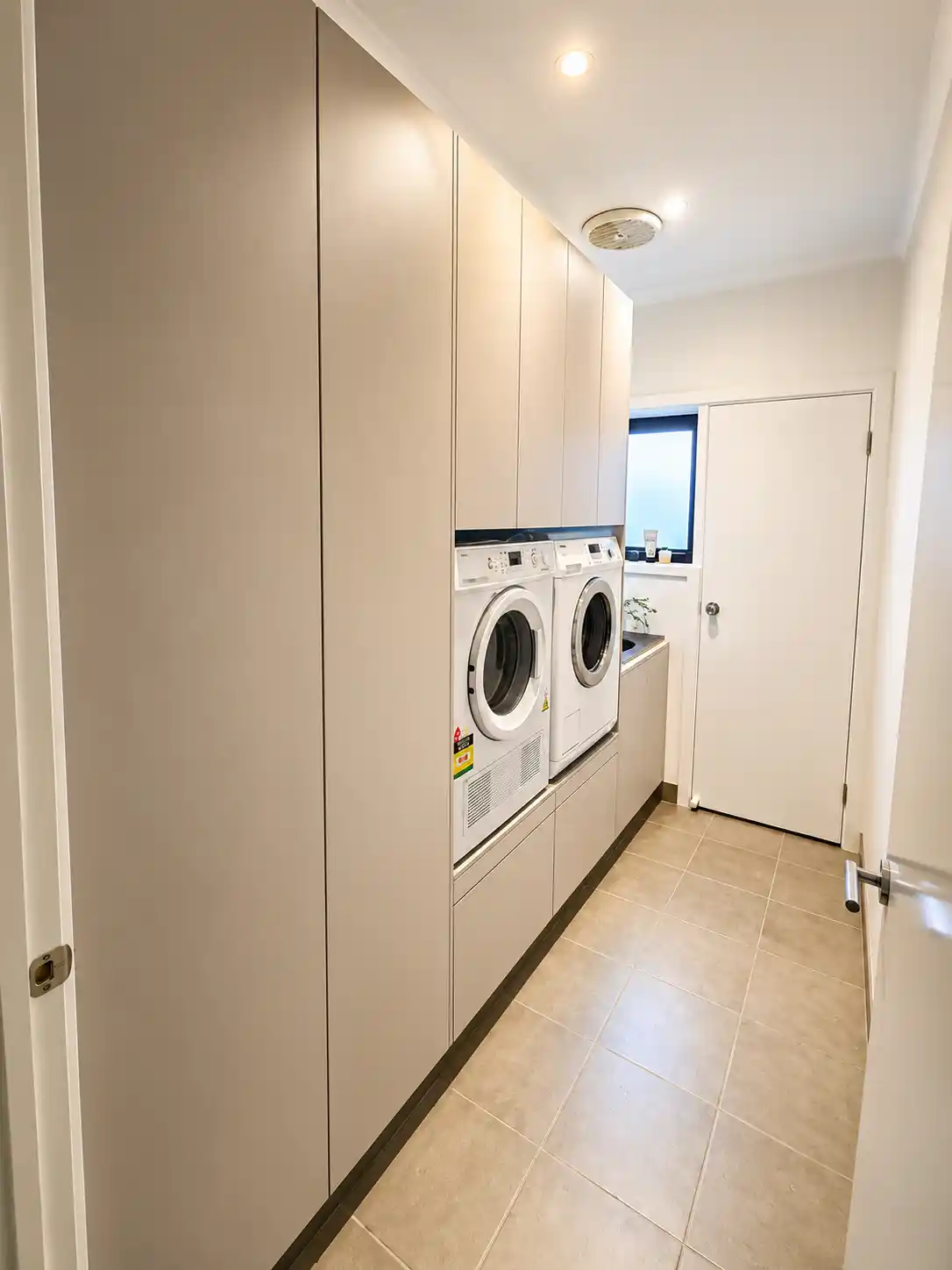 Galley laundry with floor-to-ceiling cabinetry and integrated appliances