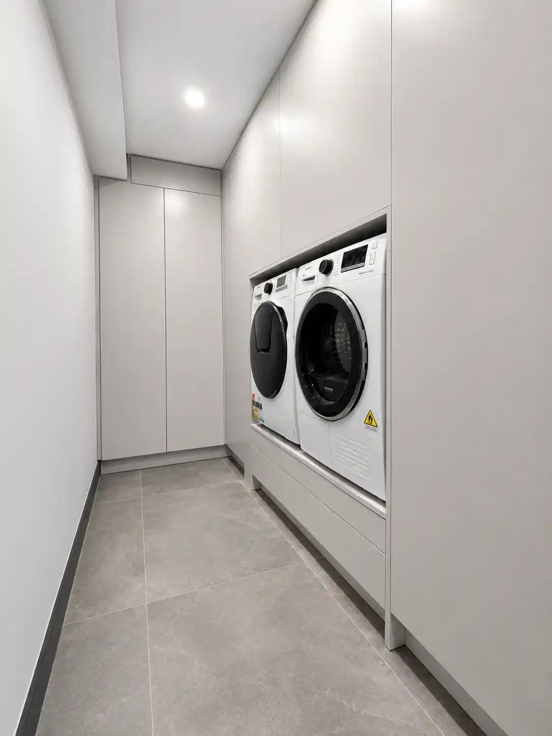 Minimal handleless laundry with recessed appliance bay