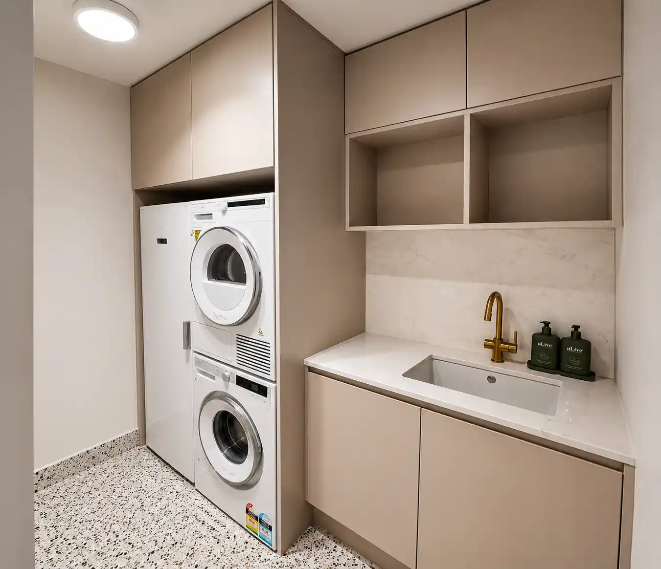 Stacked washer and dryer with tall cabinetry and stone benchtop