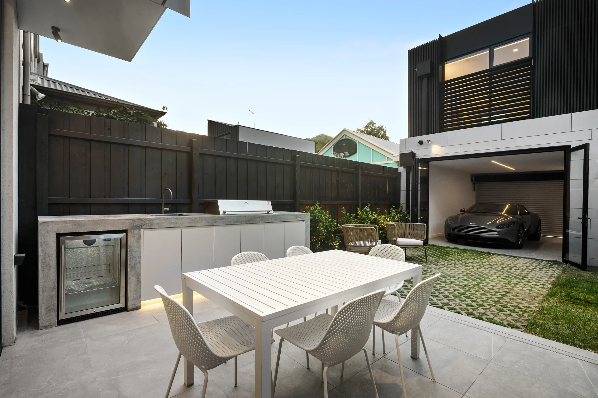 Concrete-topped outdoor kitchen with built-in BBQ and bar fridge in a courtyard