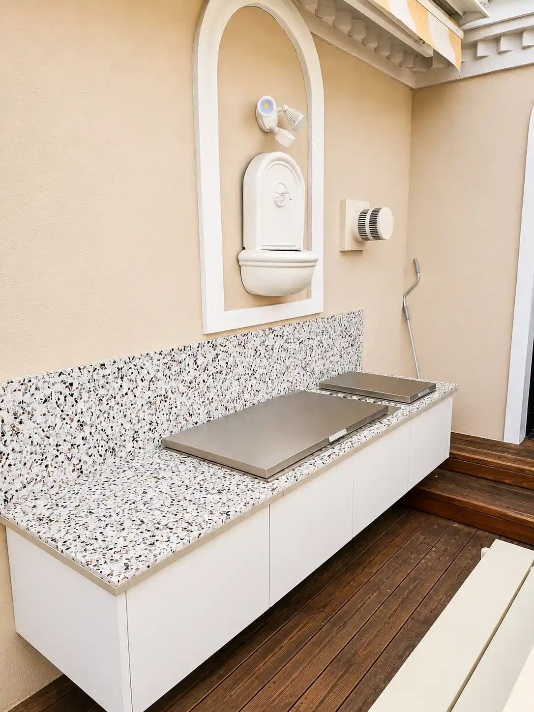 Terrazzo-topped courtyard servery with floating white cabinetry and BBQ hot plates